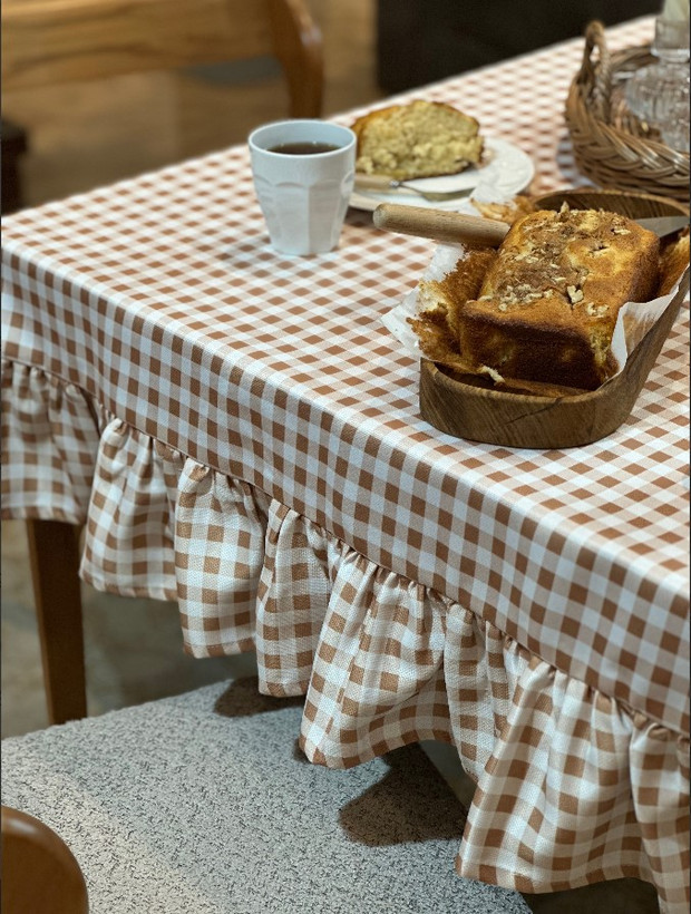 چیدمان میز ناهارخوری با رومیزی گرد چهارخانه و ظروف پذیرایی