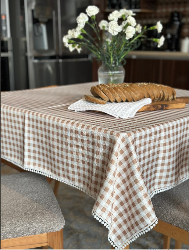 رومیزی چهارخانه نسکافهای روشن با نواردوزی منگولهدار روی میز ناهارخوری